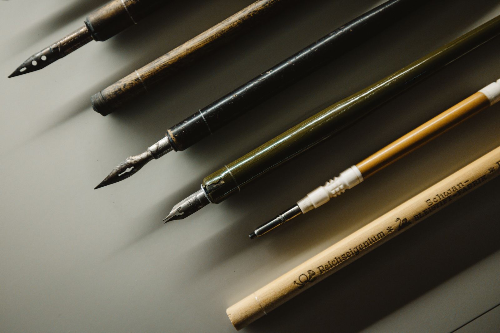 Vintage fountain pens and calligraphy nibs laid on a desk